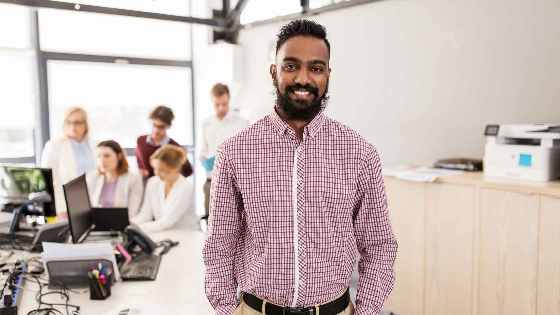 A smiling professional with a team working behind him