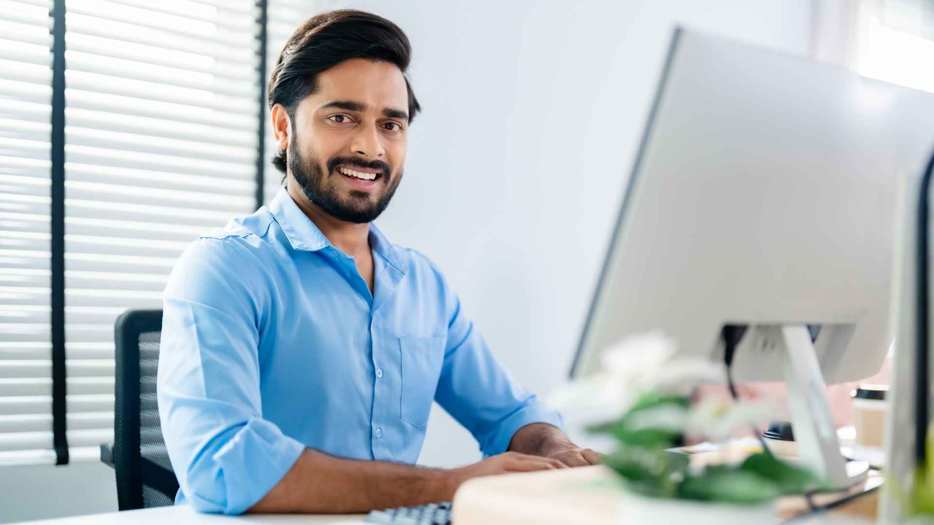 A young professional smiling while working at a computer