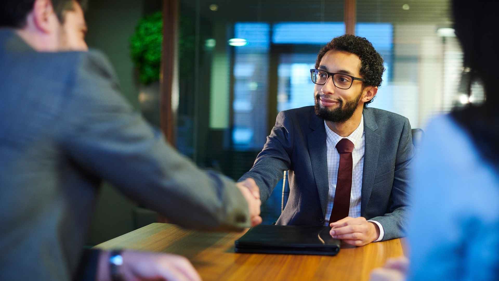 A hiring manager shaking hands with a candidate in an office
