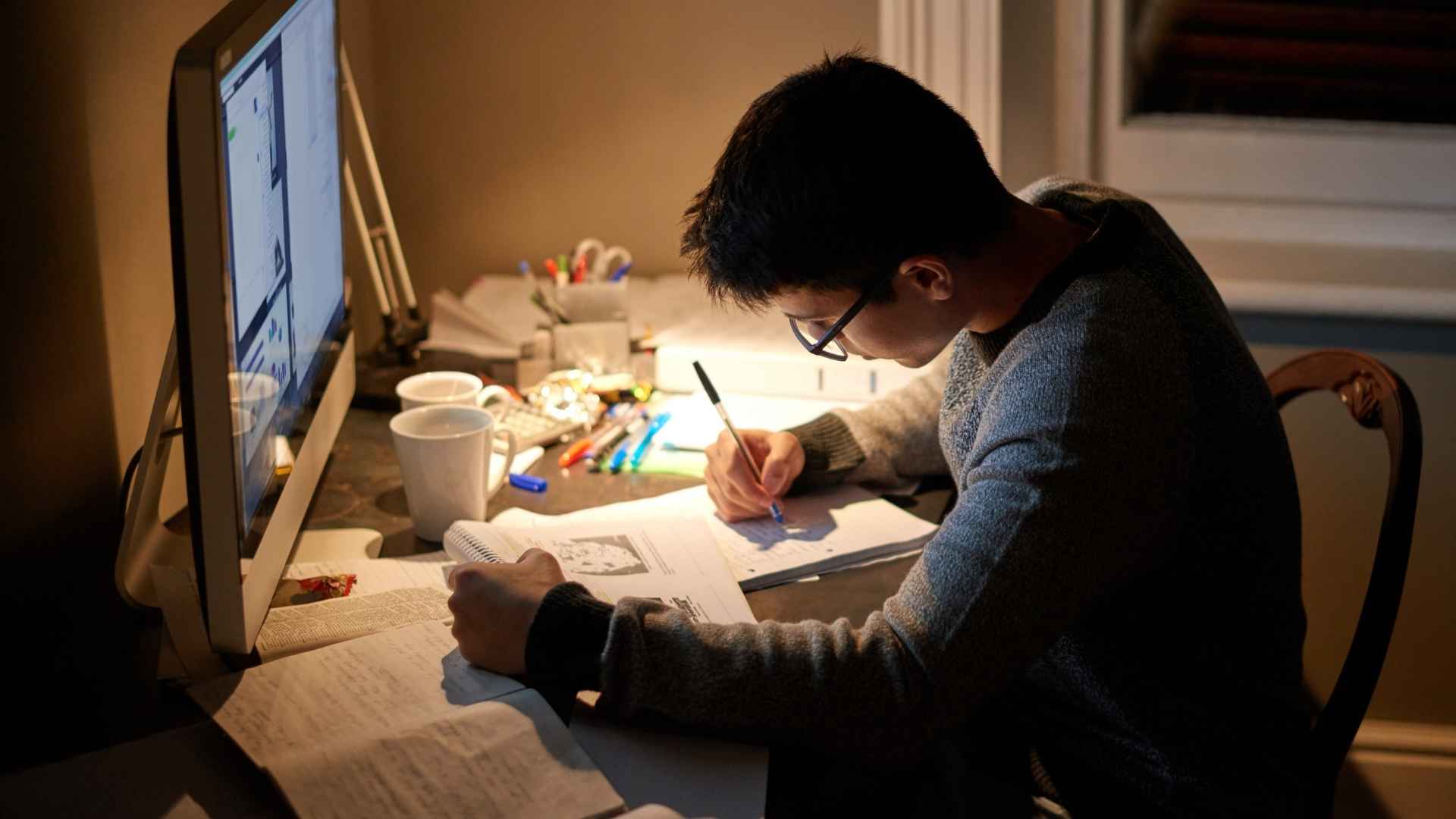 A student working late at a desk under a lamp